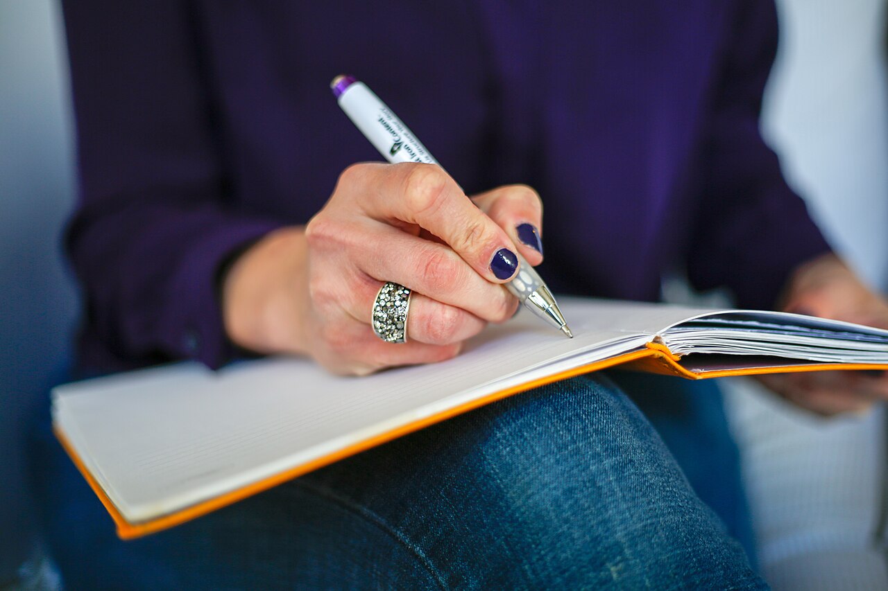 A close-up of a hand writing ideas in a notebook